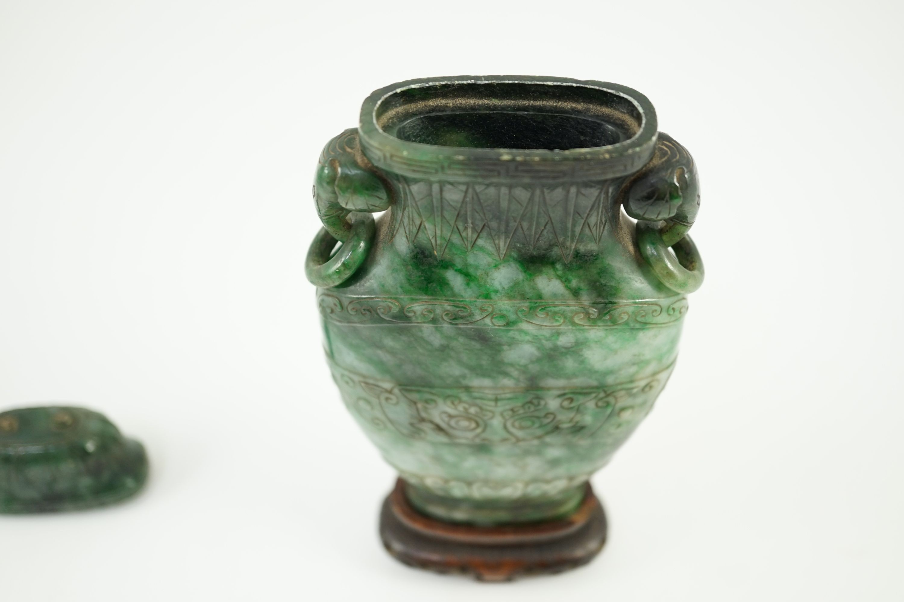 A Chinese archaistic green jadeite vase and cover, late Qing dynasty, 14.5 cm high, Silver wire inlaid wood stand, cover finial missing